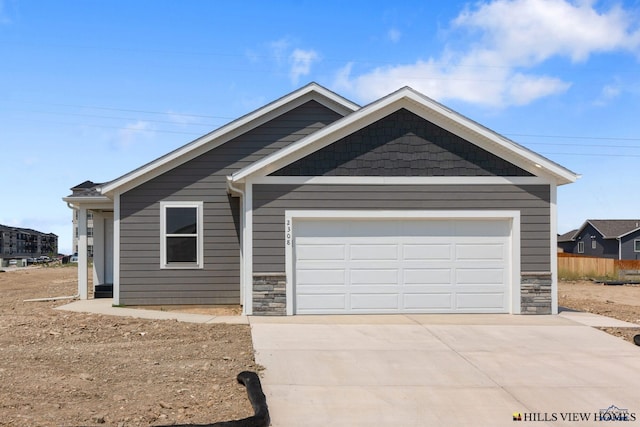 view of front of home featuring concrete driveway, a garage, and stone siding