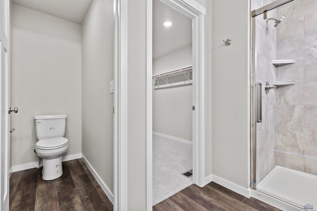 full bath featuring baseboards, a spacious closet, toilet, a shower stall, and wood finished floors