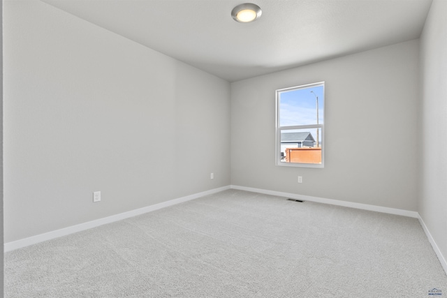 carpeted spare room featuring visible vents and baseboards