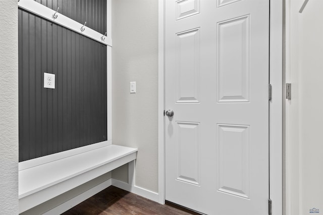 mudroom with dark wood-style flooring, baseboards, and a textured wall