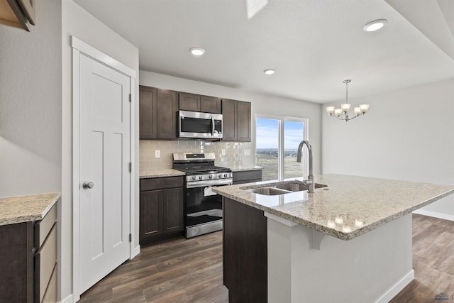 kitchen with dark wood finished floors, dark brown cabinets, appliances with stainless steel finishes, a sink, and backsplash