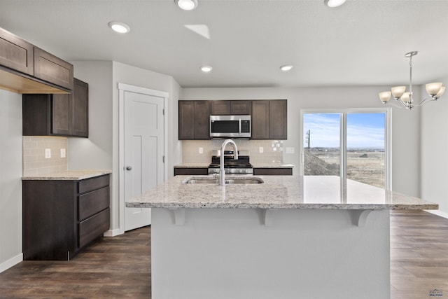 kitchen featuring stainless steel microwave, a sink, dark wood finished floors, and dark brown cabinetry