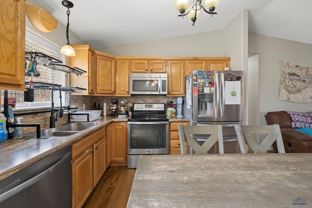 kitchen featuring tasteful backsplash, a notable chandelier, lofted ceiling, appliances with stainless steel finishes, and wood finished floors
