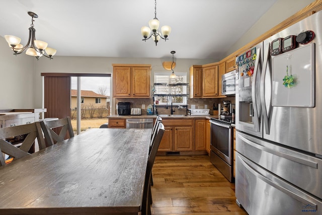 kitchen featuring wood-type flooring, a notable chandelier, a sink, and appliances with stainless steel finishes