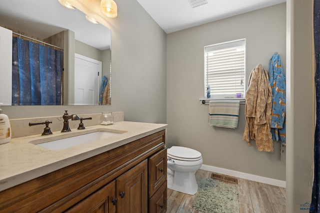 bathroom with vanity, baseboards, toilet, visible vents, and wood finished floors