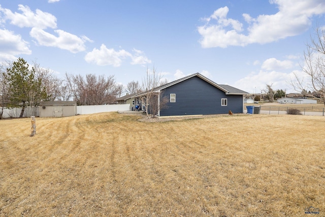 exterior space featuring a shed, a yard, a fenced backyard, and an outbuilding