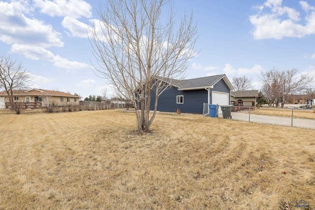 view of yard with an attached garage, fence, and concrete driveway