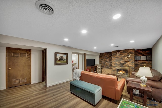 3112 Flint Dr, Rapid City, SD 57702 - living area featuring recessed lighting, a textured ceiling, a brick fireplace, visible vents, and wood finished floors