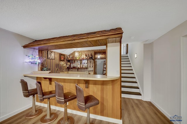 3112 Flint Dr, Rapid City, SD 57702 - bar featuring a textured ceiling, wet bar, wood finished floors, stairs, and baseboards