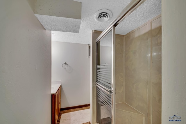 3112 Flint Dr, Rapid City, SD 57702 - full bath featuring a textured ceiling, vanity, visible vents, a stall shower, and baseboards