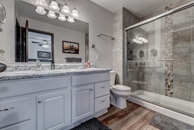 full bath with a sink, a stall shower, and wood finished floors