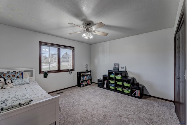 carpeted bedroom featuring visible vents, baseboards, a ceiling fan, and a textured ceiling