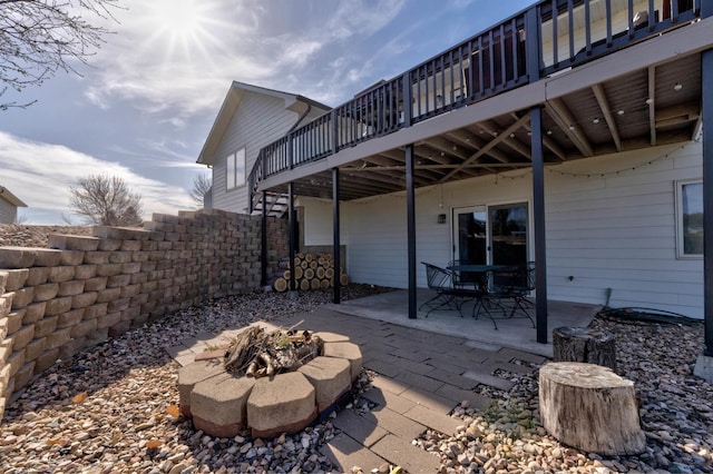 view of patio featuring a deck, fence, and a fire pit