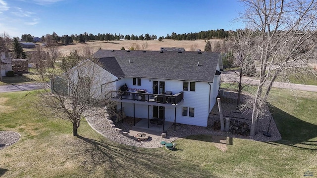 rear view of house with a yard, a shingled roof, a deck, and a patio