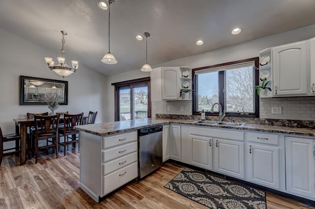 kitchen with a peninsula, white cabinetry, vaulted ceiling, dishwasher, and a sink