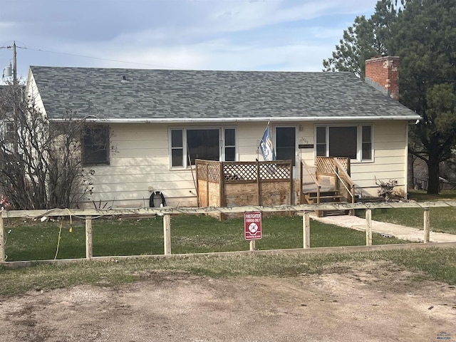 view of front of house featuring a chimney, a front lawn, roof with shingles, and covered porch