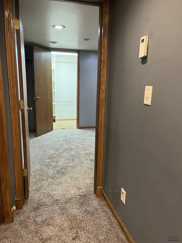 corridor with baseboards and carpet