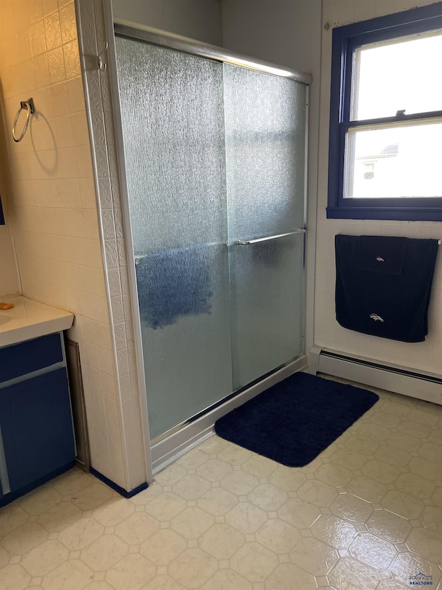 full bathroom featuring a baseboard radiator, vanity, tile patterned floors, and a stall shower