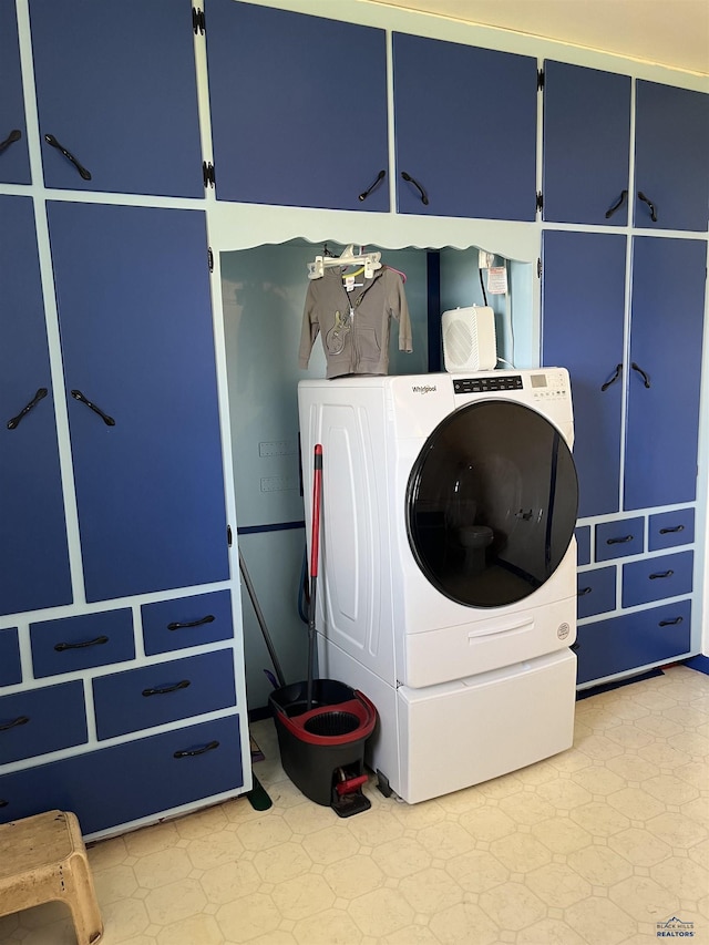 laundry area featuring cabinet space, light floors, and washer / clothes dryer