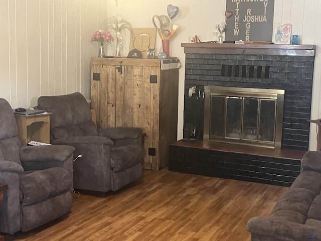 living room featuring wood walls, a brick fireplace, and wood finished floors