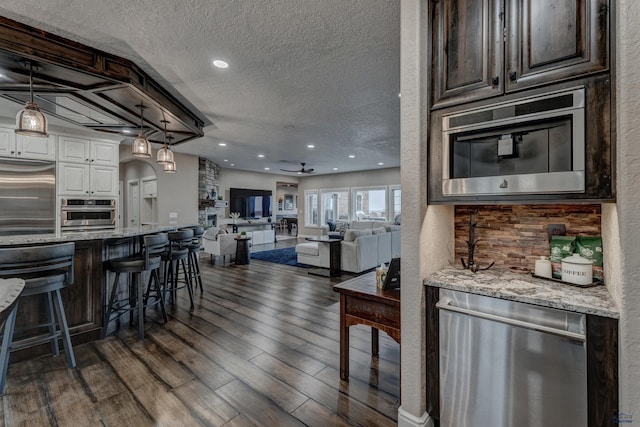 1334 Alta Vista Dr, Rapid City, SD 57701 - kitchen with dark wood-style floors, a kitchen breakfast bar, light stone counters, and appliances with stainless steel finishes