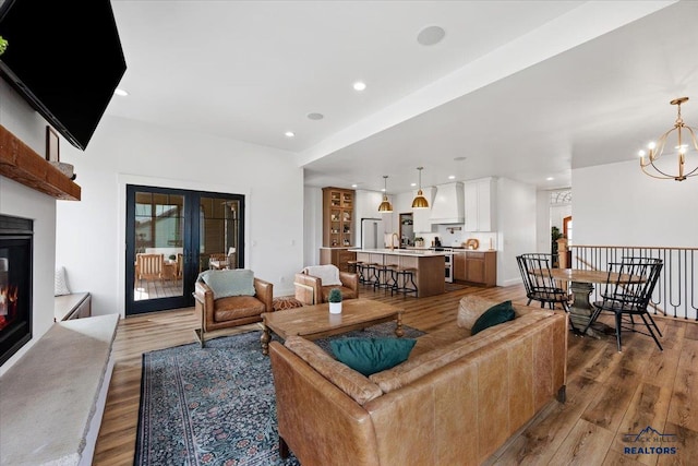 living area featuring french doors, recessed lighting, a glass covered fireplace, and light wood-style floors