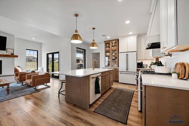 kitchen with light countertops, white appliances, a sink, and open floor plan