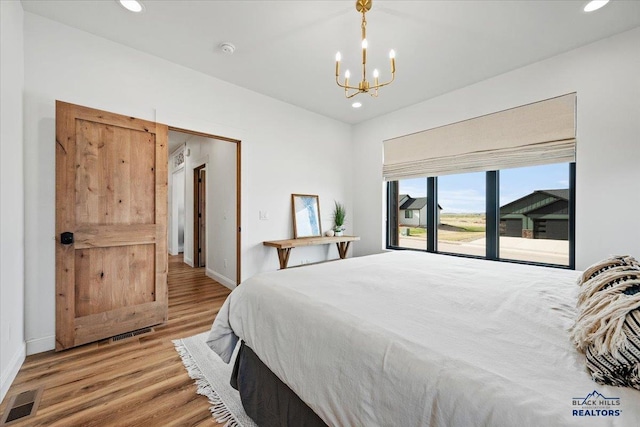 bedroom with light wood-type flooring, baseboards, an inviting chandelier, recessed lighting, and visible vents