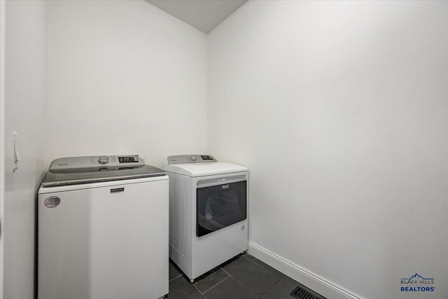 washroom featuring laundry area, dark tile patterned flooring, visible vents, washer and dryer, and baseboards