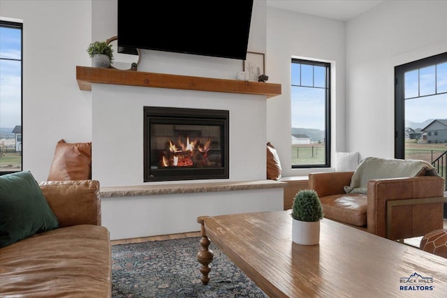 living room featuring a glass covered fireplace, plenty of natural light, and wood finished floors
