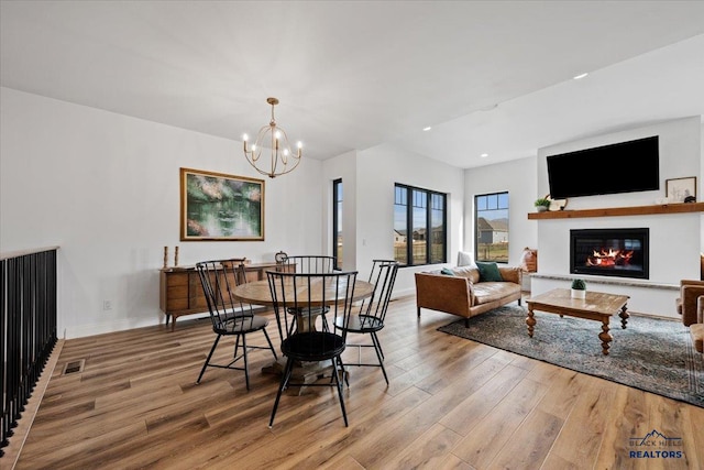dining space with a glass covered fireplace, baseboards, a chandelier, and wood finished floors