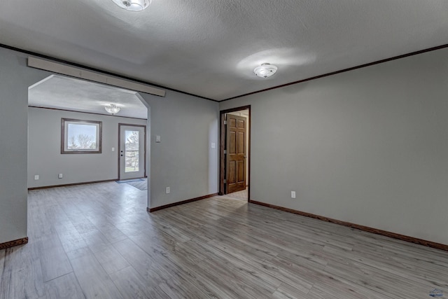 7497 Tanager Dr, Rapid City, SD 57702 - spare room featuring ornamental molding, baseboards, light wood-type flooring, and arched walkways