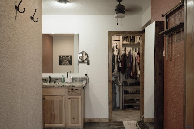 2412 Cameron Dr, Rapid City, SD 57702 - bathroom with a walk in closet, a ceiling fan, vanity, and a textured wall