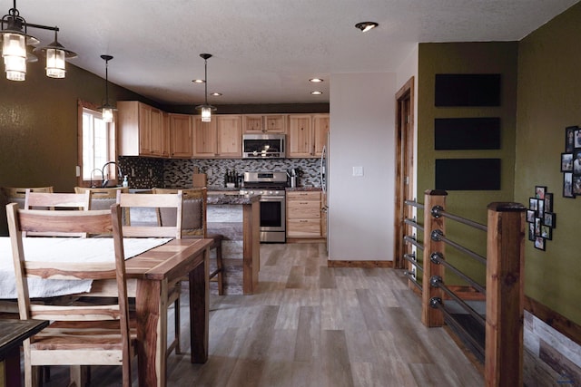 2412 Cameron Dr, Rapid City, SD 57702 - kitchen with tasteful backsplash, light brown cabinets, dark countertops, appliances with stainless steel finishes, and light wood-style floors