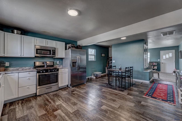 1021 Haines Ave, Rapid City, SD 57701 - kitchen with dark wood-type flooring, white cabinetry, visible vents, stainless steel appliances, and baseboards