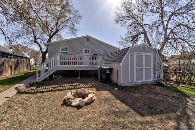 1021 Haines Ave, Rapid City, SD 57701 - back of property featuring a gambrel roof, a wooden deck, an outbuilding, a storage unit, and fence