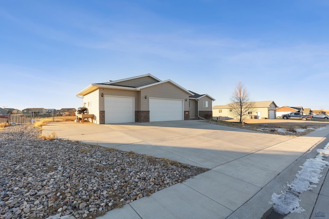 exterior space with concrete driveway, a residential view, brick siding, a garage, and fence