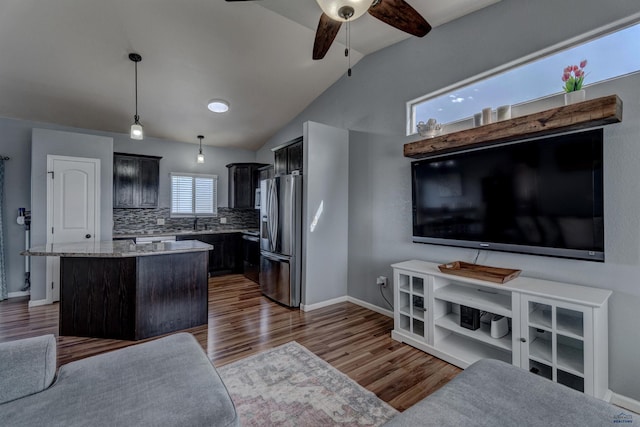 kitchen featuring stainless steel fridge with ice dispenser, a kitchen island, decorative backsplash, open floor plan, and ceiling fan
