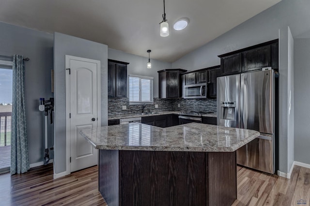 kitchen featuring backsplash, lofted ceiling, appliances with stainless steel finishes, and light wood-style floors