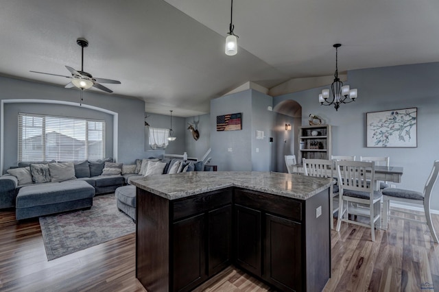 kitchen featuring lofted ceiling, light wood finished floors, arched walkways, pendant lighting, and ceiling fan with notable chandelier