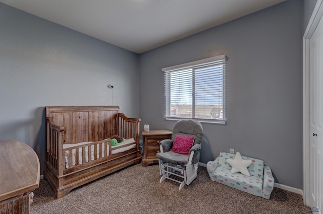 carpeted bedroom with a crib and baseboards