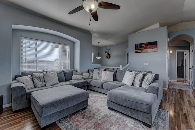 living area featuring vaulted ceiling, wood finished floors, arched walkways, baseboards, and ceiling fan