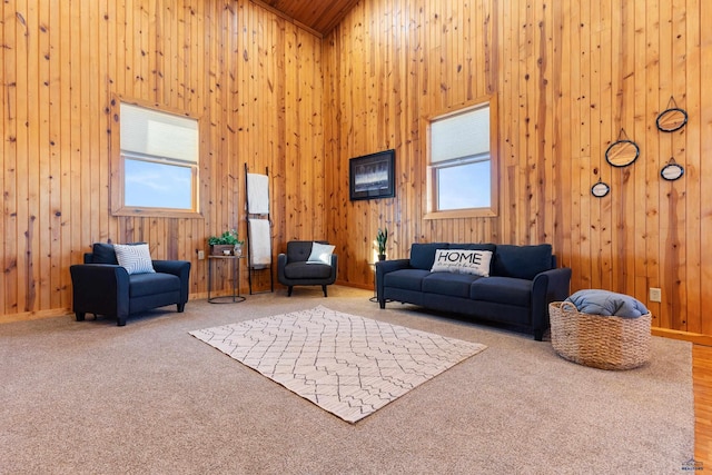 living room featuring plenty of natural light, a high ceiling, wood walls, and carpet