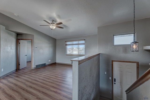 foyer featuring vaulted ceiling, wood finished floors, visible vents, a ceiling fan, and baseboards