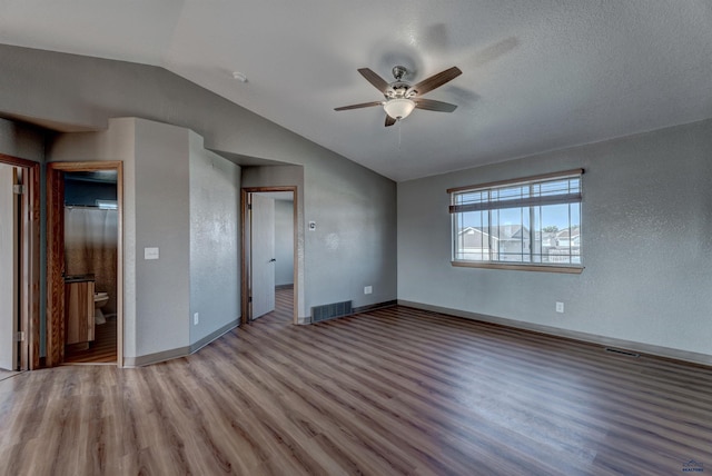 unfurnished bedroom with lofted ceiling, wood finished floors, visible vents, baseboards, and ceiling fan