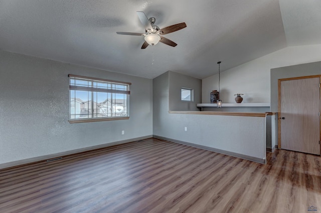 unfurnished living room featuring baseboards, visible vents, lofted ceiling, wood finished floors, and ceiling fan