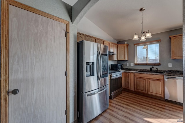 kitchen with stainless steel appliances, vaulted ceiling, a sink, arched walkways, and light wood-style flooring