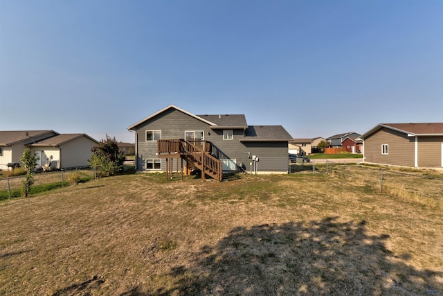 rear view of house featuring stairway, a fenced backyard, a residential view, a wooden deck, and a lawn