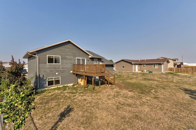 back of property with a lawn, a wooden deck, fence, and stairs