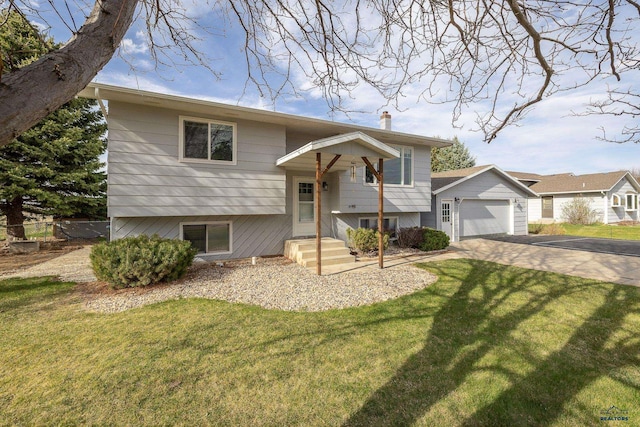 bi-level home featuring a detached garage, driveway, a front yard, and fence